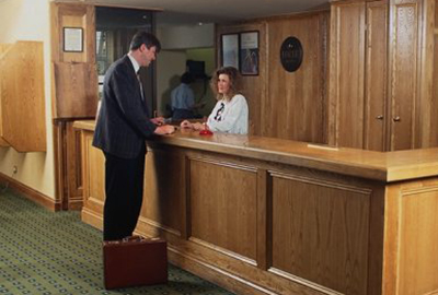 Front desk agent greets hotel guest in training video.